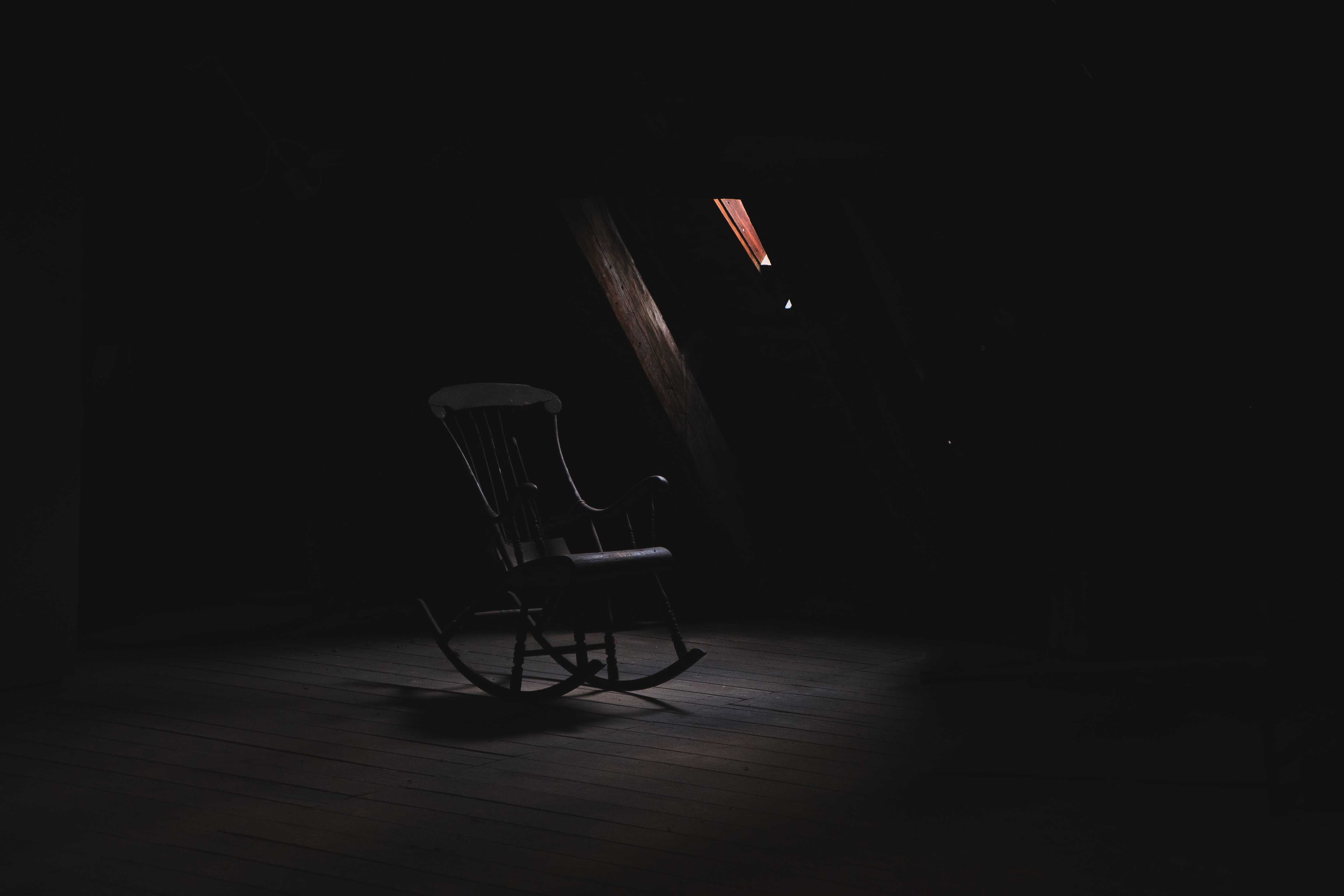 A grey chair sits in an old attic in a haunted scene