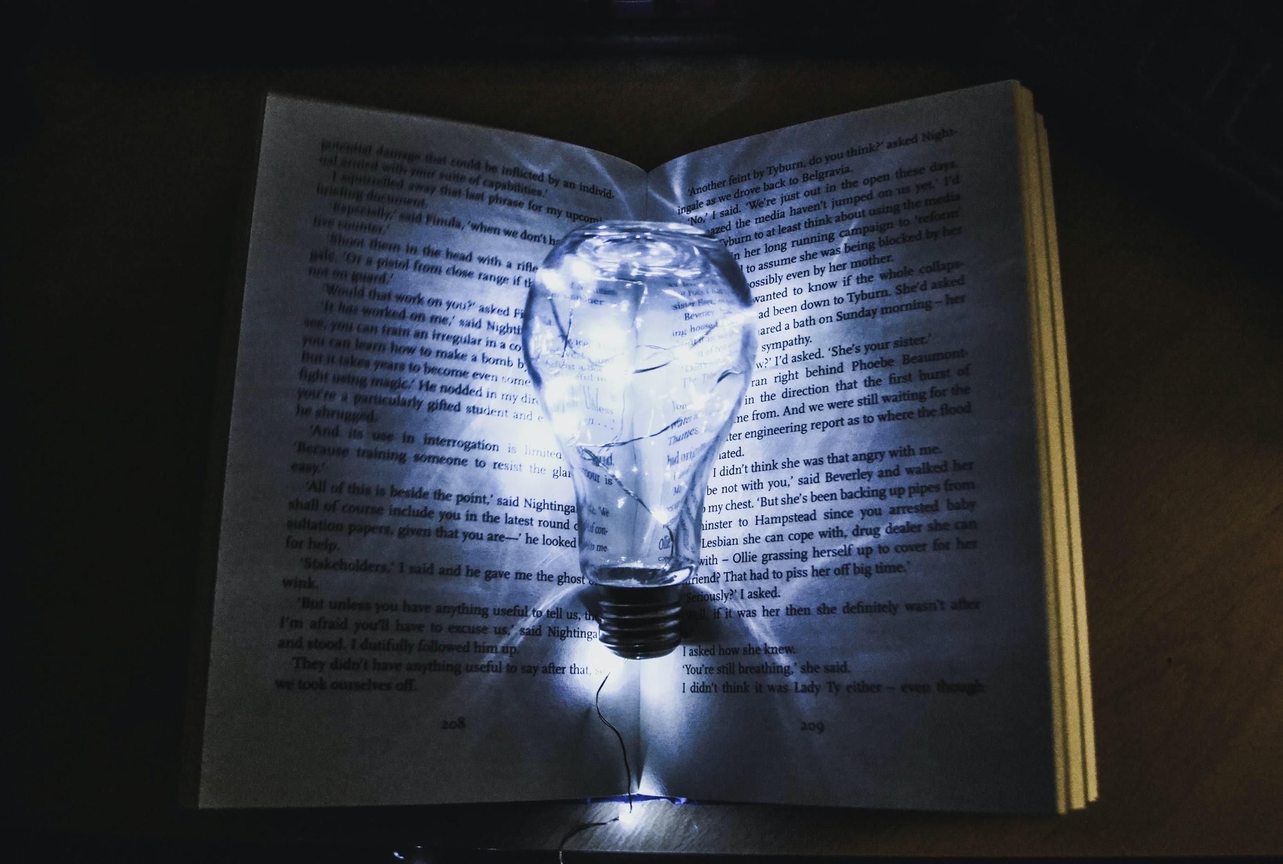 Light bulb in front of a book in a dark room