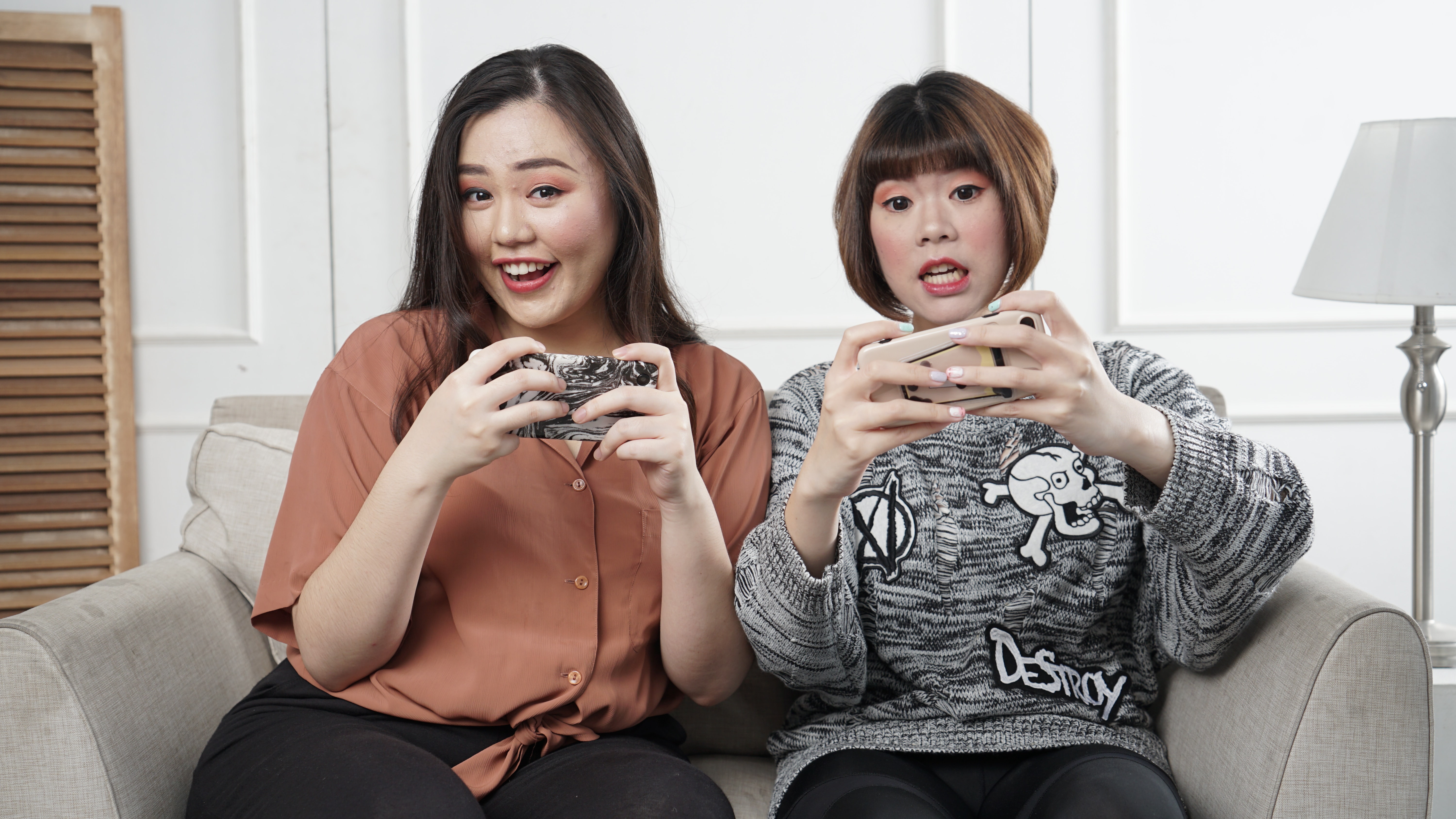 Two girls sitting on the couch and playing online games