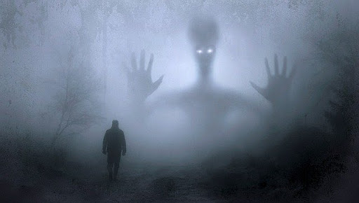 A man walking in the mysterious forest watched by an alien in the background