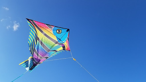 A colorful fish-shaped kite is flying in the sky