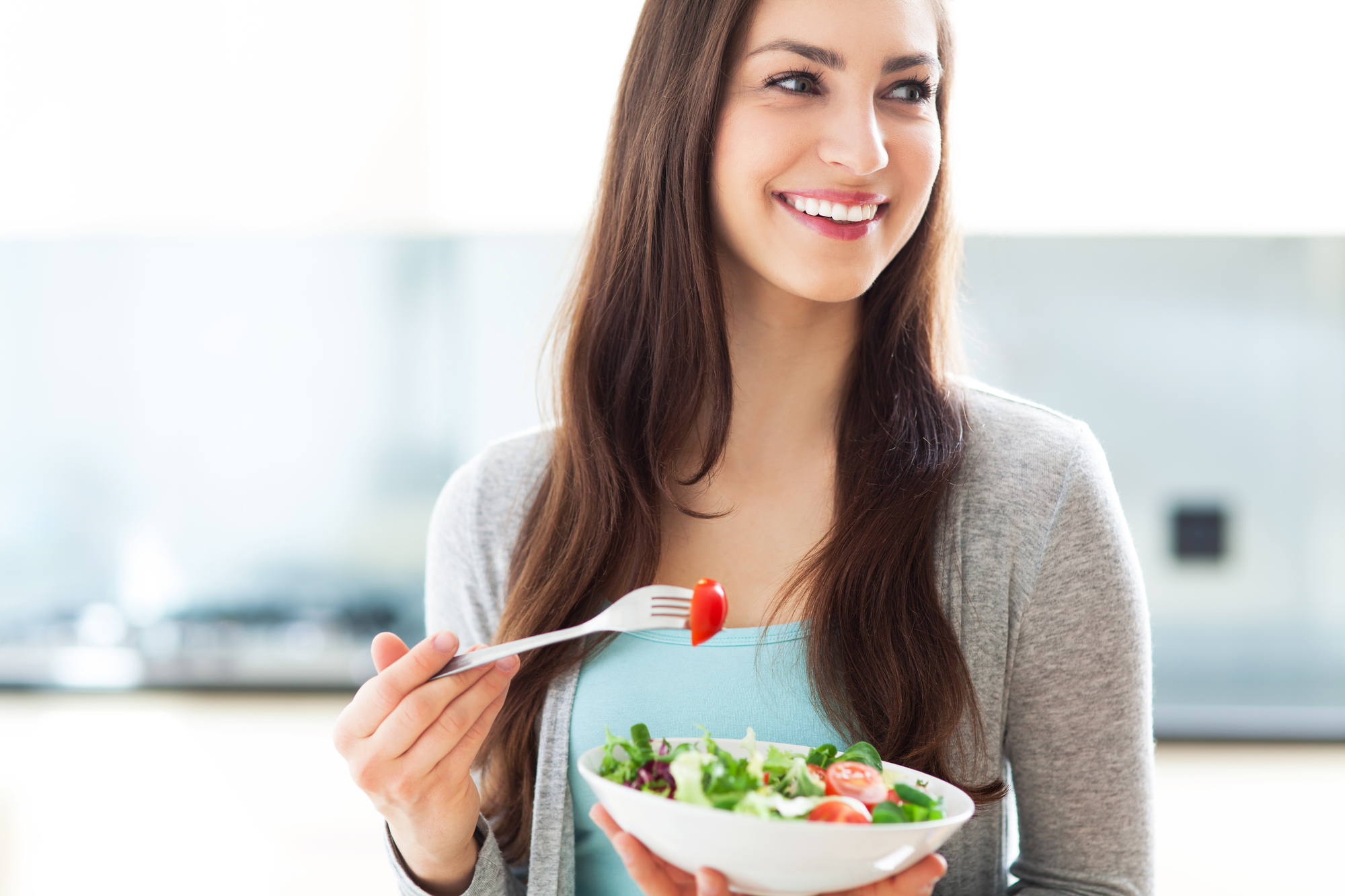 A woman looking happy and not stressed out while eating a healthy snack. 