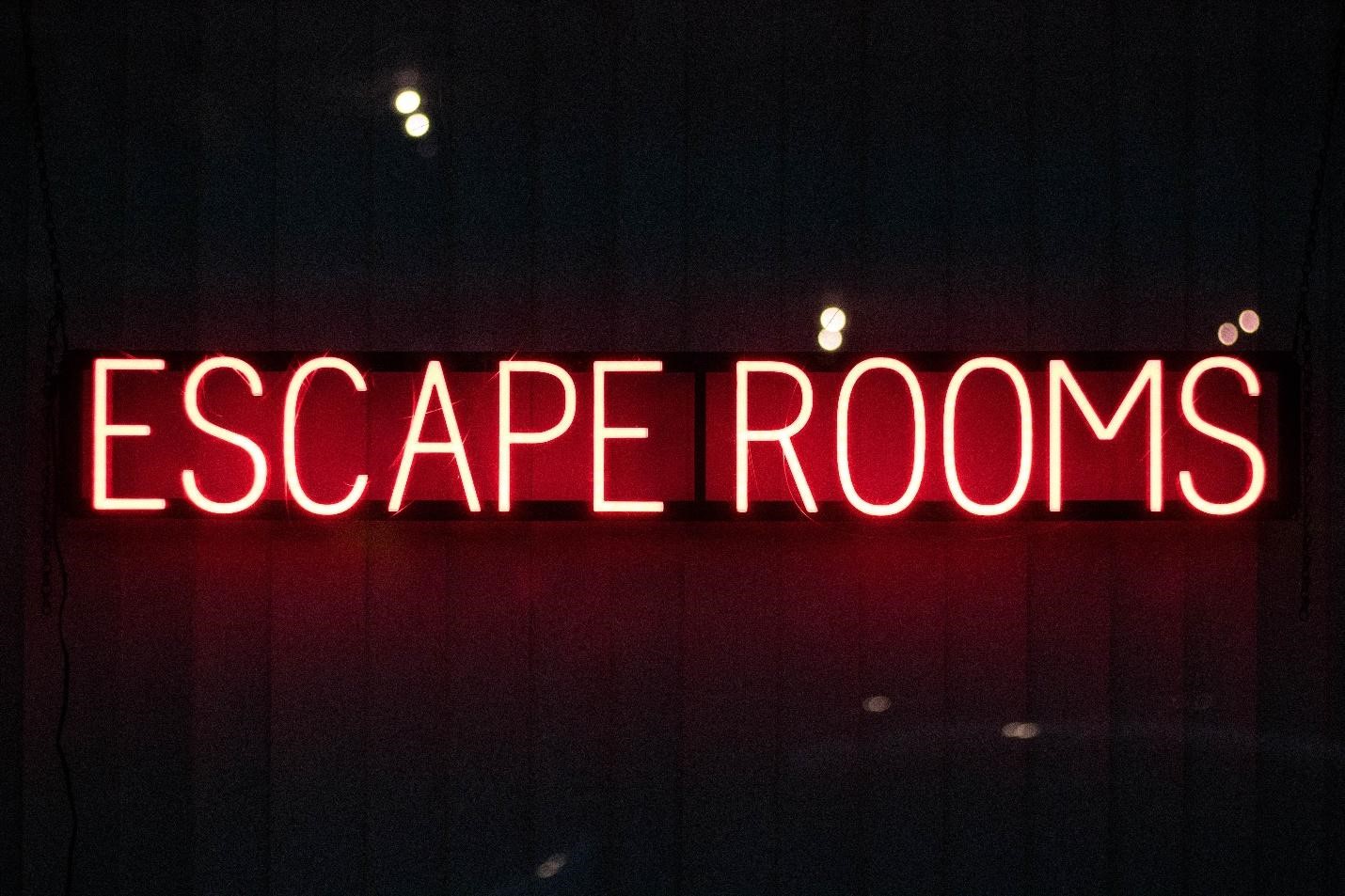 A wall lit with neon style text reading Escape Room
