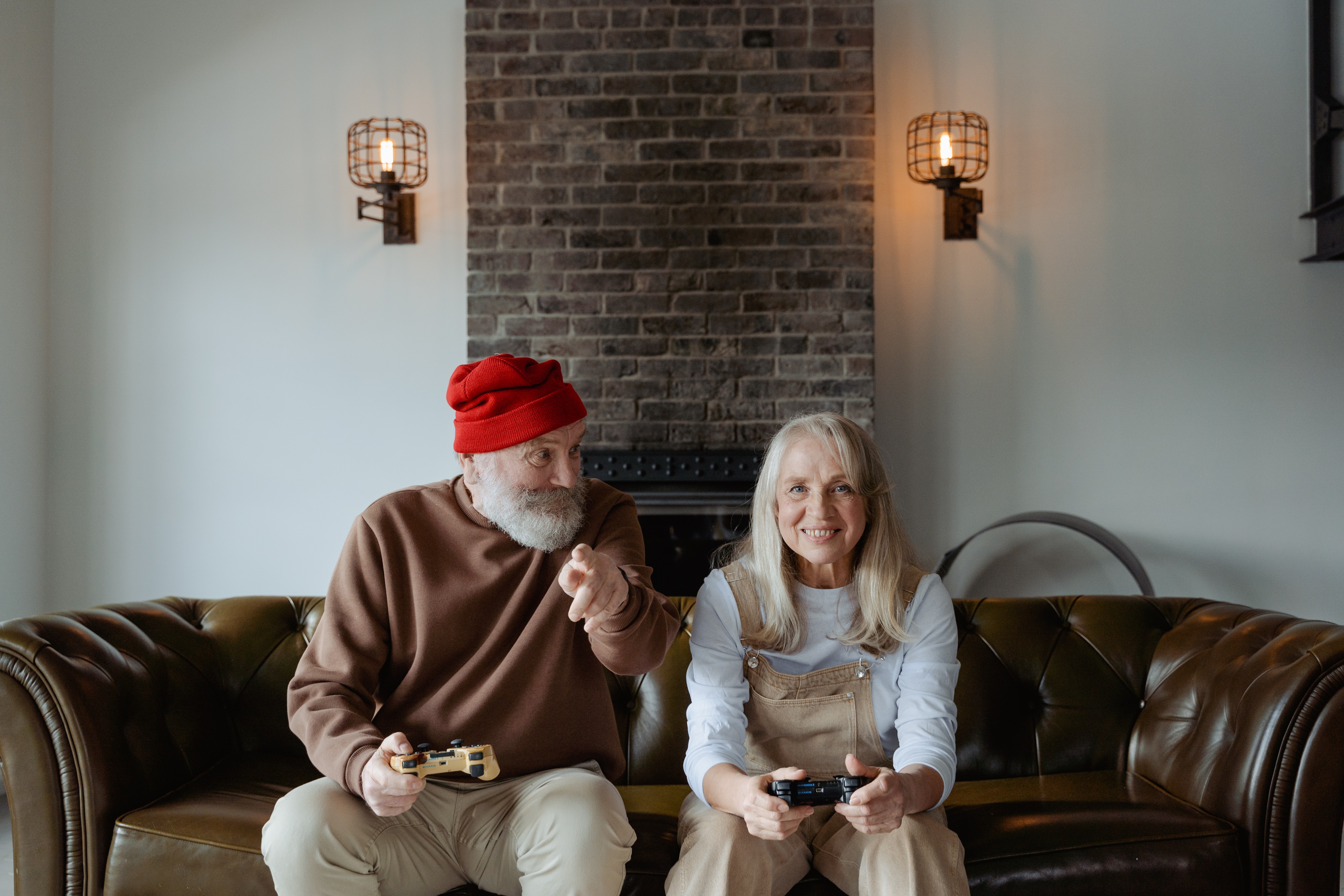 Elderly couple gaming on couch man in red beanie 