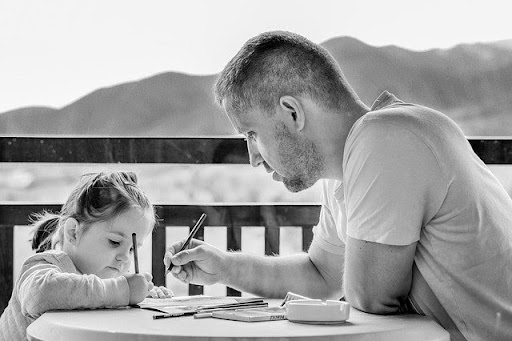 Little girl with her father drawing