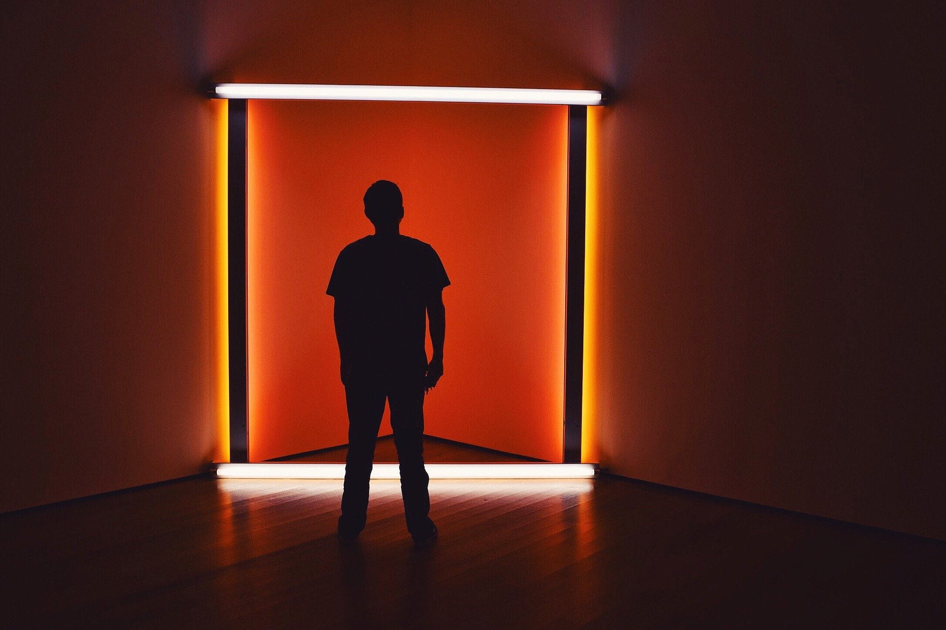 man’s silhouette in a dark room, in orange colored fluorescent lights